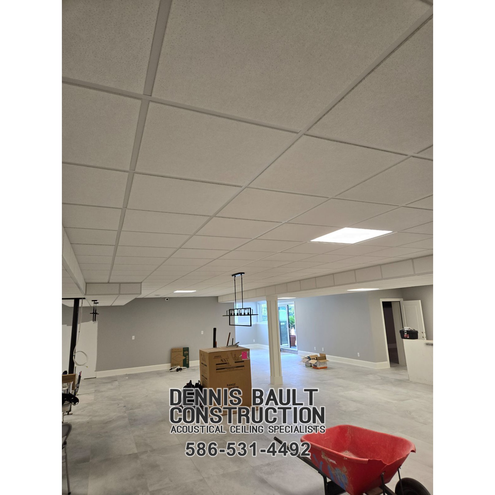 Looking up at the completed residential walk-out basement ceiling, the acoustical tiles fit perfectly within the drop ceiling grid. The clean, seamless surface reflects soft lighting, enhancing the room's brightness and modern appeal. The precise alignment of tiles creates a polished, professional look, blending functionality with style for a comfortable, sound-controlled living space.