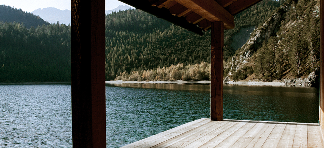 A scenic dock over calm water with mountains in the background.