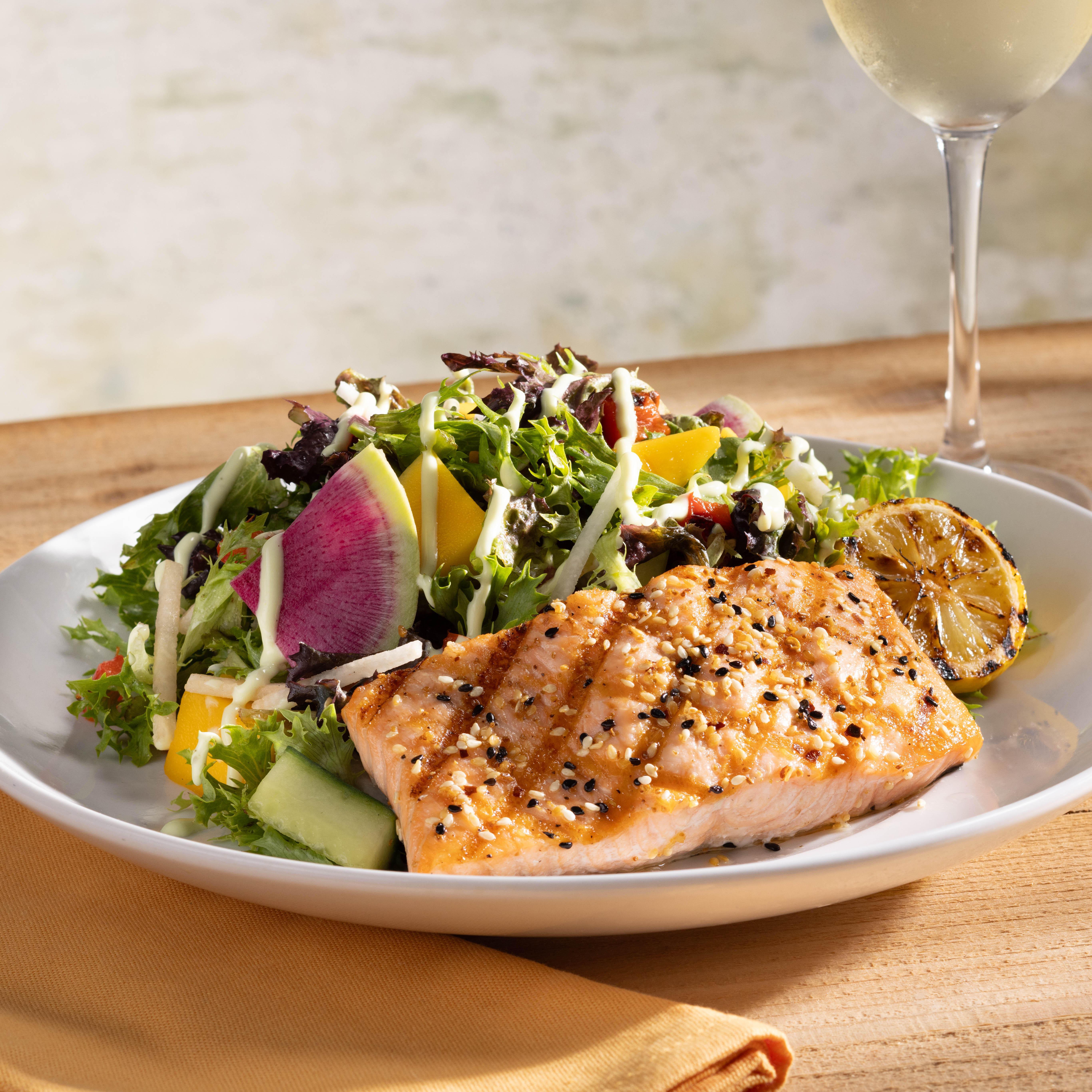 Sesame Grilled Salmon Salad features organic greens, mango, jicama, lemongrass sauce and toasted sesame dressing.