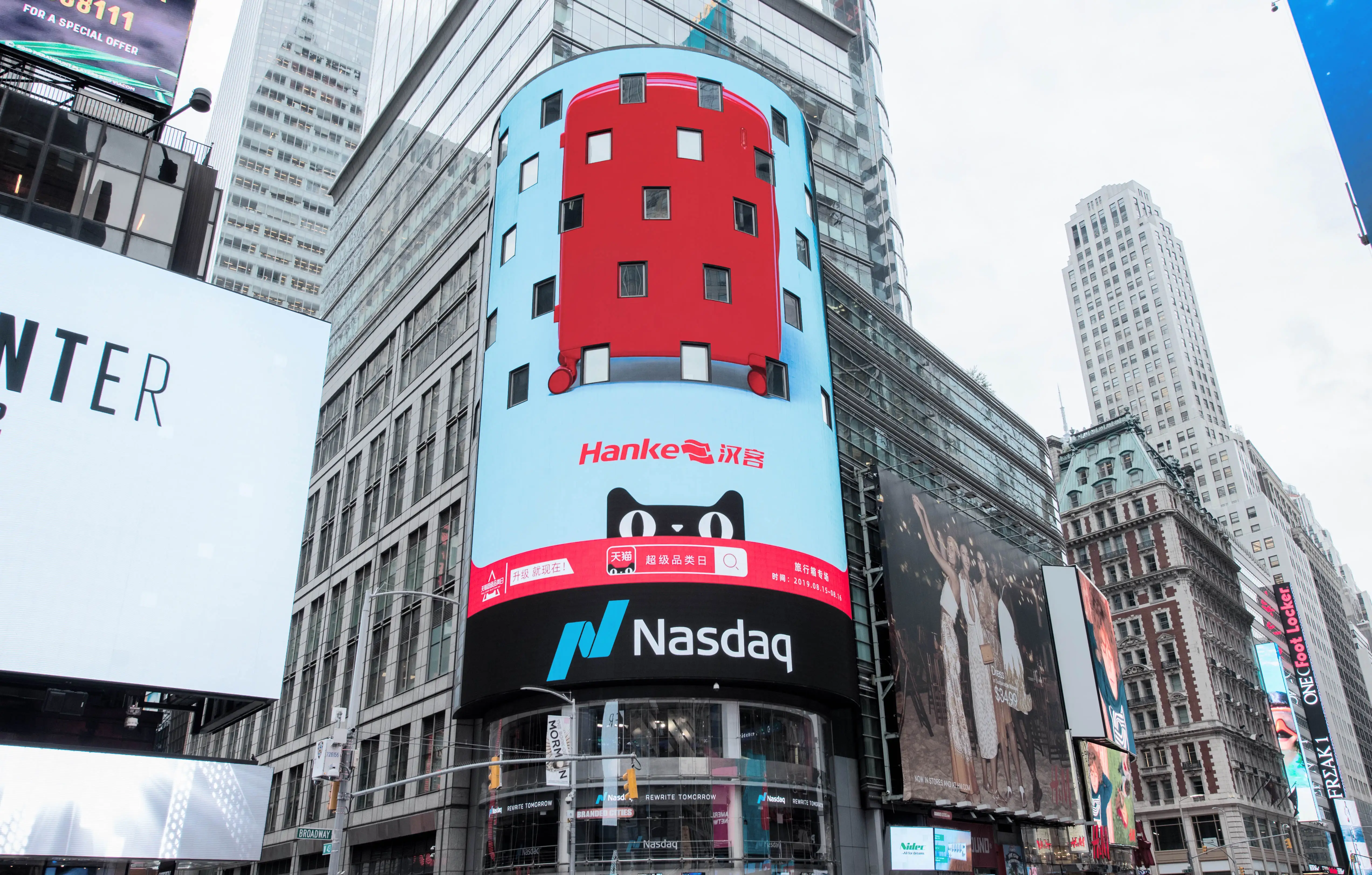 A collection of billboards and tall buildings, characteristic of a busy city like Times Square. One prominent billboard displays a stylized, colorful building facade with red and light blue panels and small square windows. Below this, a large black billboard features the Nasdaq logo, a blue 'N' graphic, and the word 'Nasdaq' in white text. Other billboards show advertisements for brands like Hanke, as well as images of people and text. The architecture varies from modern glass skyscrapers to older, ornate brick buildings, creating a dense urban landscape.