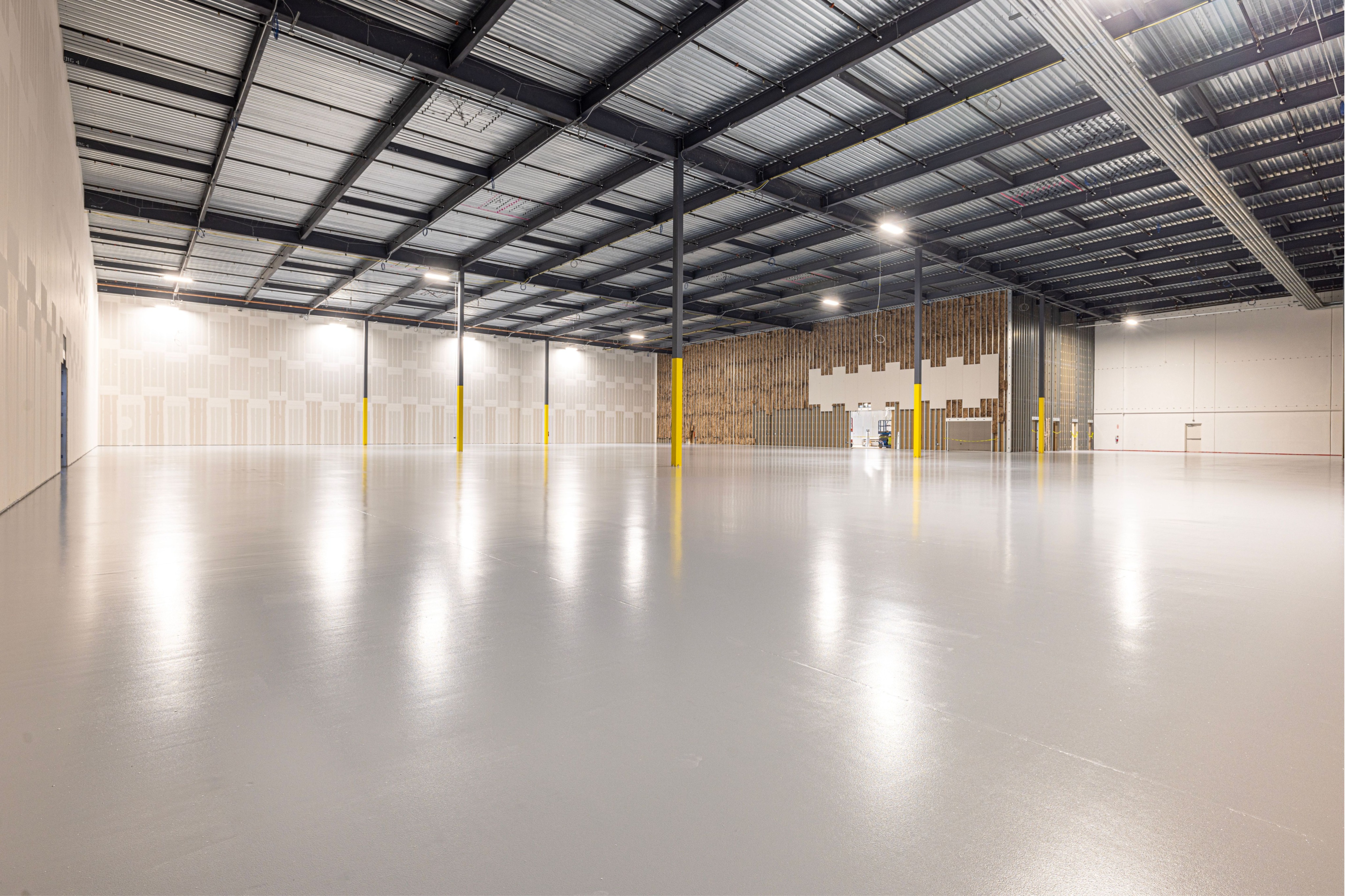 Large commercial space featuring a smooth, seamless floor coating with a clean, polished appearance. This image represents Crest & Crown LLC’s epoxy and full flake flooring solutions for warehouses, workshops, and other commercial environments.