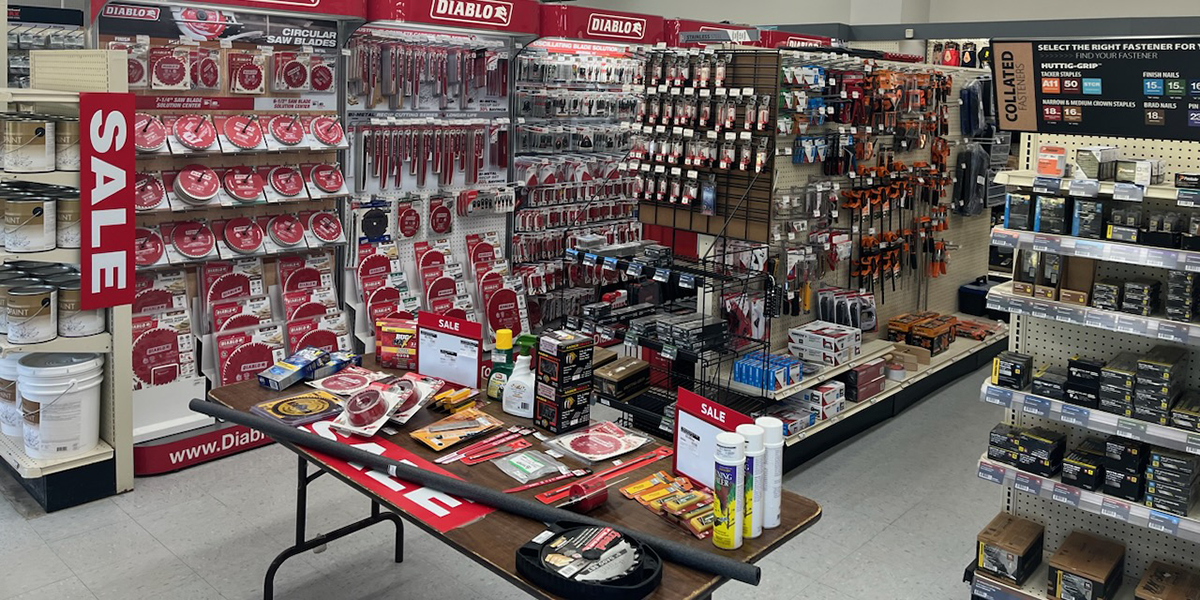 An assortment of Diablo saw blades, fasteners, and hardware accessories on sale at Builders FirstSource. The display is arranged with vibrant "SALE" signs, showcasing a variety of tools and construction materials for home improvement and building projects.