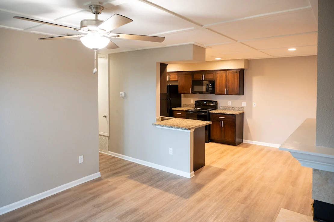 A kitchen area with a fan and wooden flooring