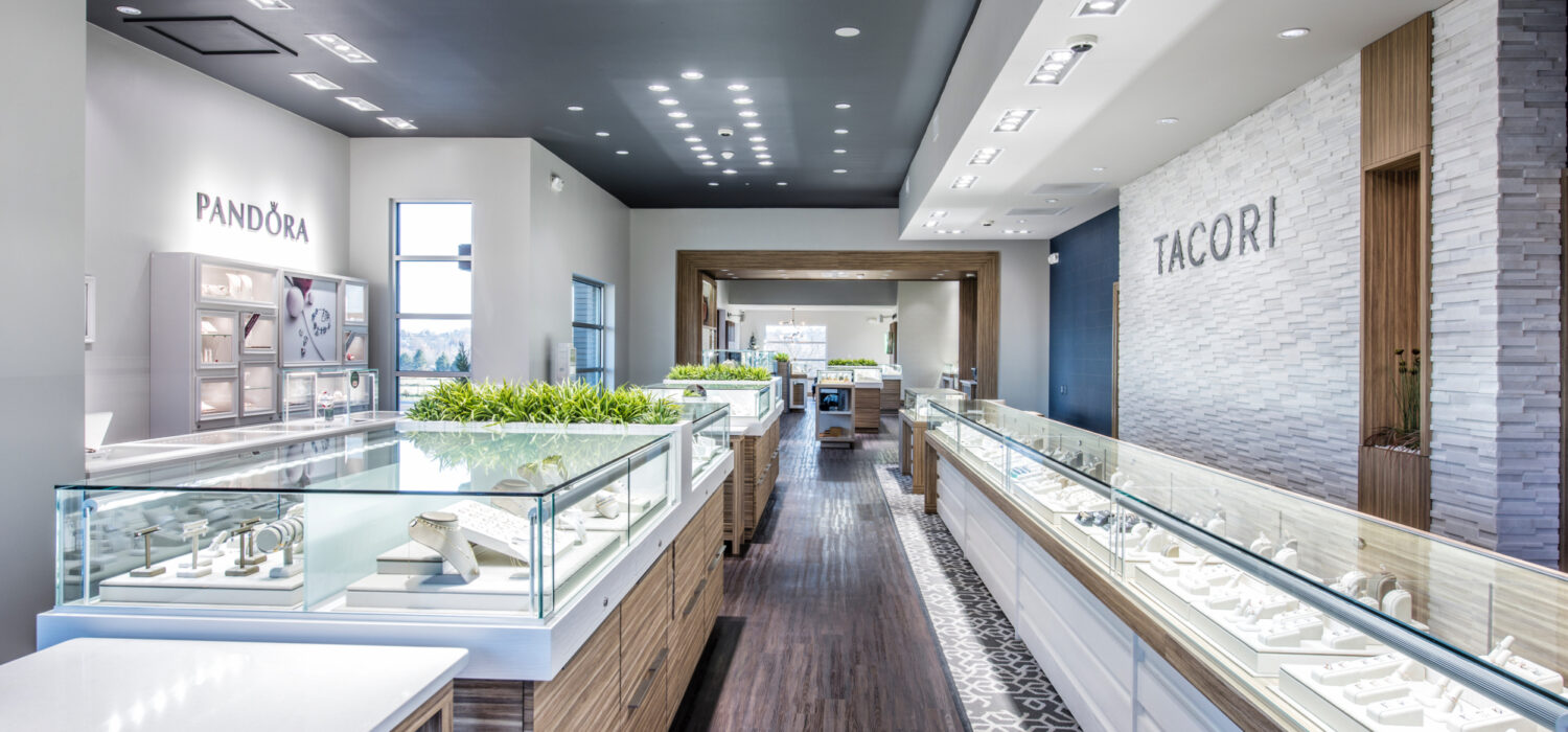 This expansive project resulted in a larger showroom, additional office space, a vault, a client consultation room, and guest restroom. Inside, you will find the latest trends in jewelry store design and technology. Together with the interior remodel, the entry was revamped, including new back-lit LED metal signage. Guests enter the store beneath a unique new cladding material—a rainscreen wood system called Machiche (Machee-chay) which is a long-lasting Brazilian hardwood.
Since re-opening, Mitchum Jewelers has seen a huge spike in foot traffic as well as sales. With the additional space, they’ve been able to grow their staff, introduce new lines of jewelry, and are enjoying new flexibility in how they showcase products and interact with customers.