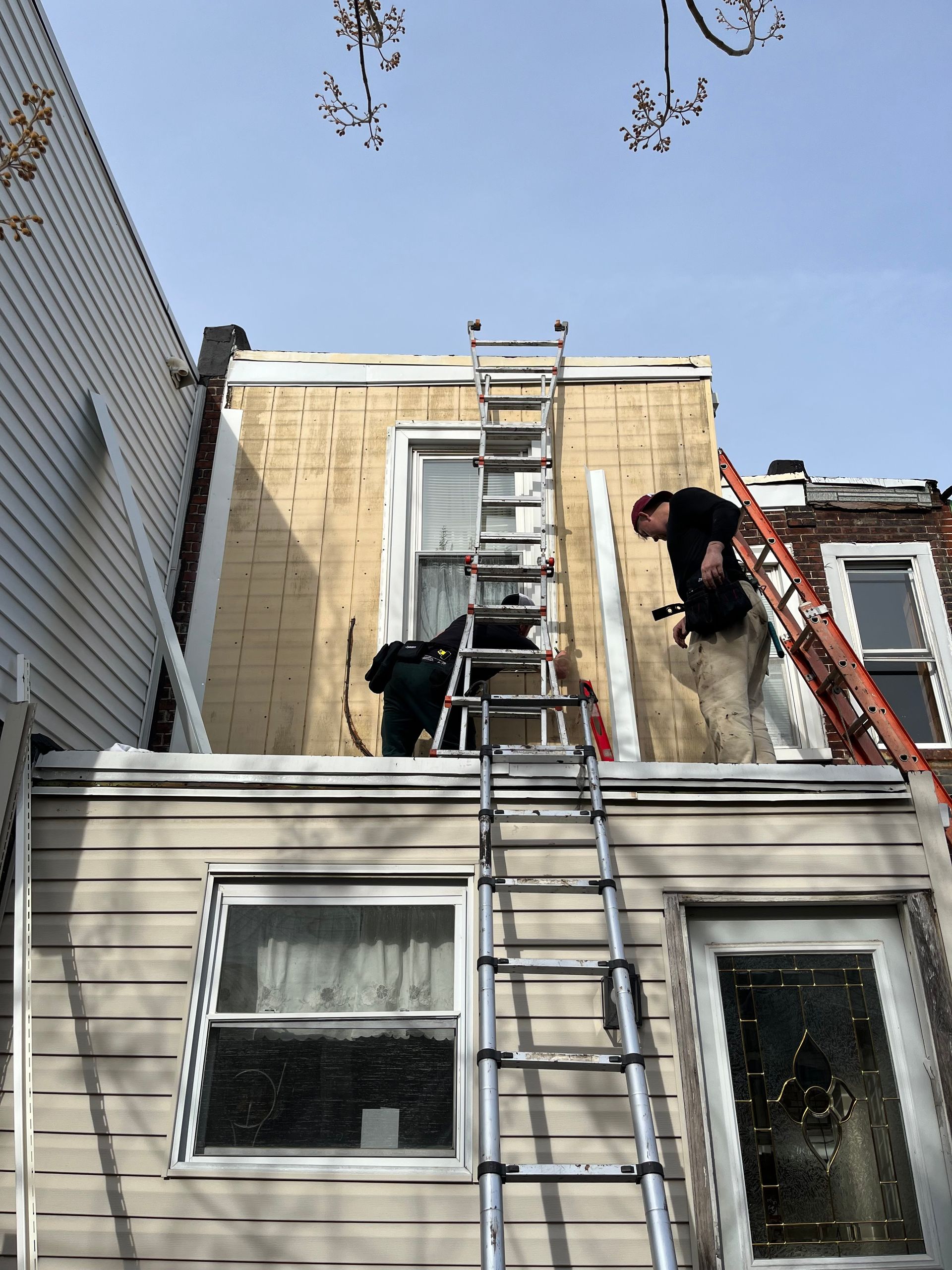 Construction professionals install exterior materials and complete renovation work using ladders and 