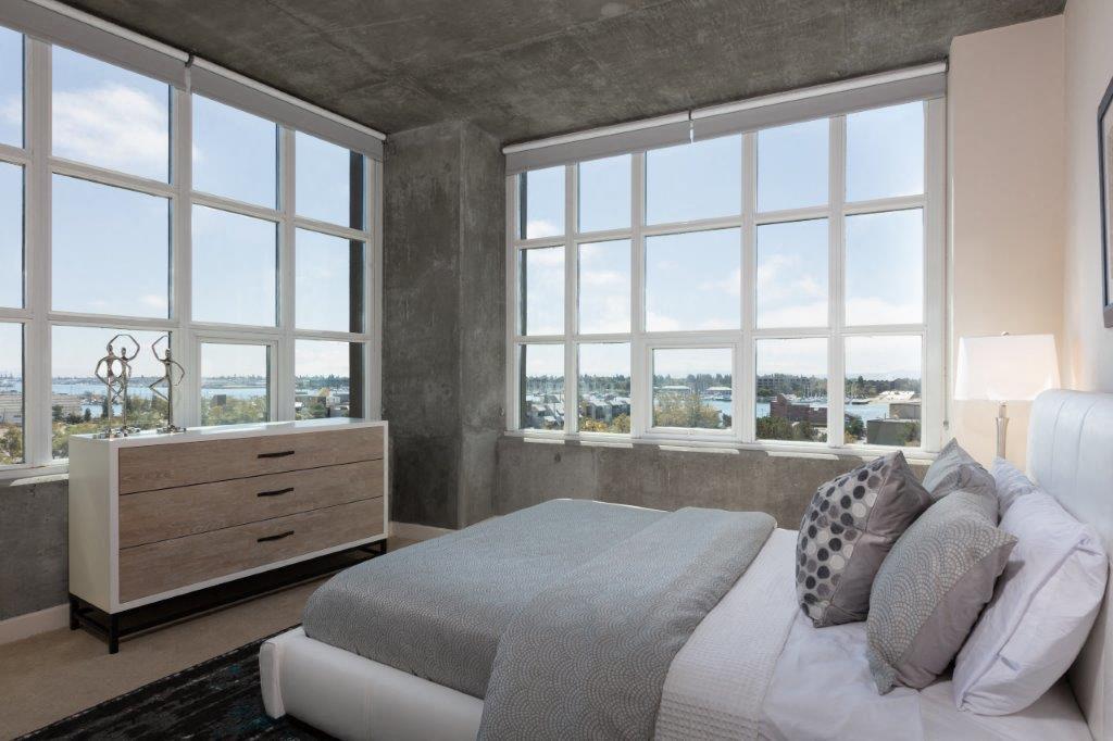 One-Bedroom Apartments in Oakland, CA - Aqua Via - Furnished Bedroom with 2 Large Windows, Plush Carpeting, and Stylish Decor