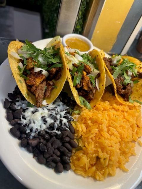 Three authentic street tacos topped with fresh cilantro and onions, served with Mexican rice, black beans, and salsa at Catramex Restaurant.