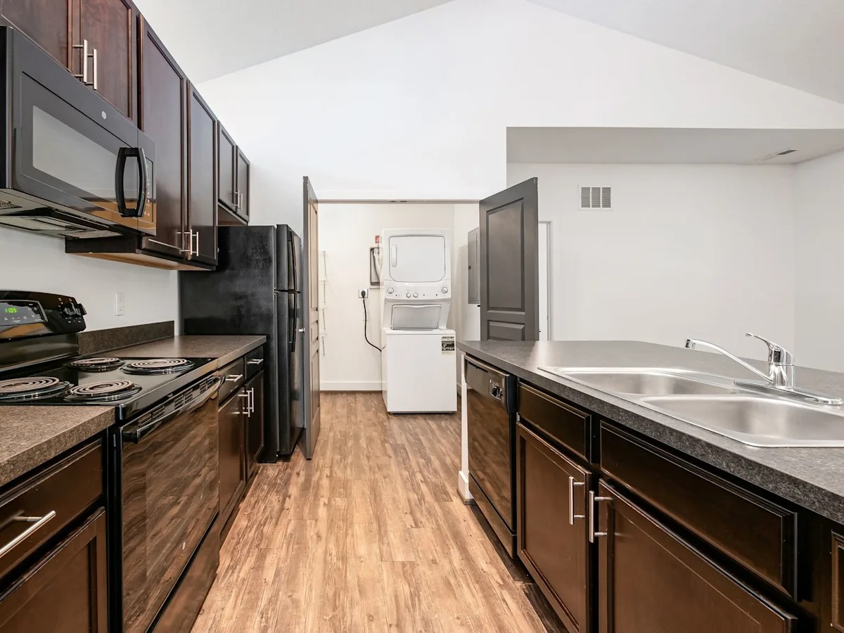 A kitchen with dark wood cabinets and black appliances.