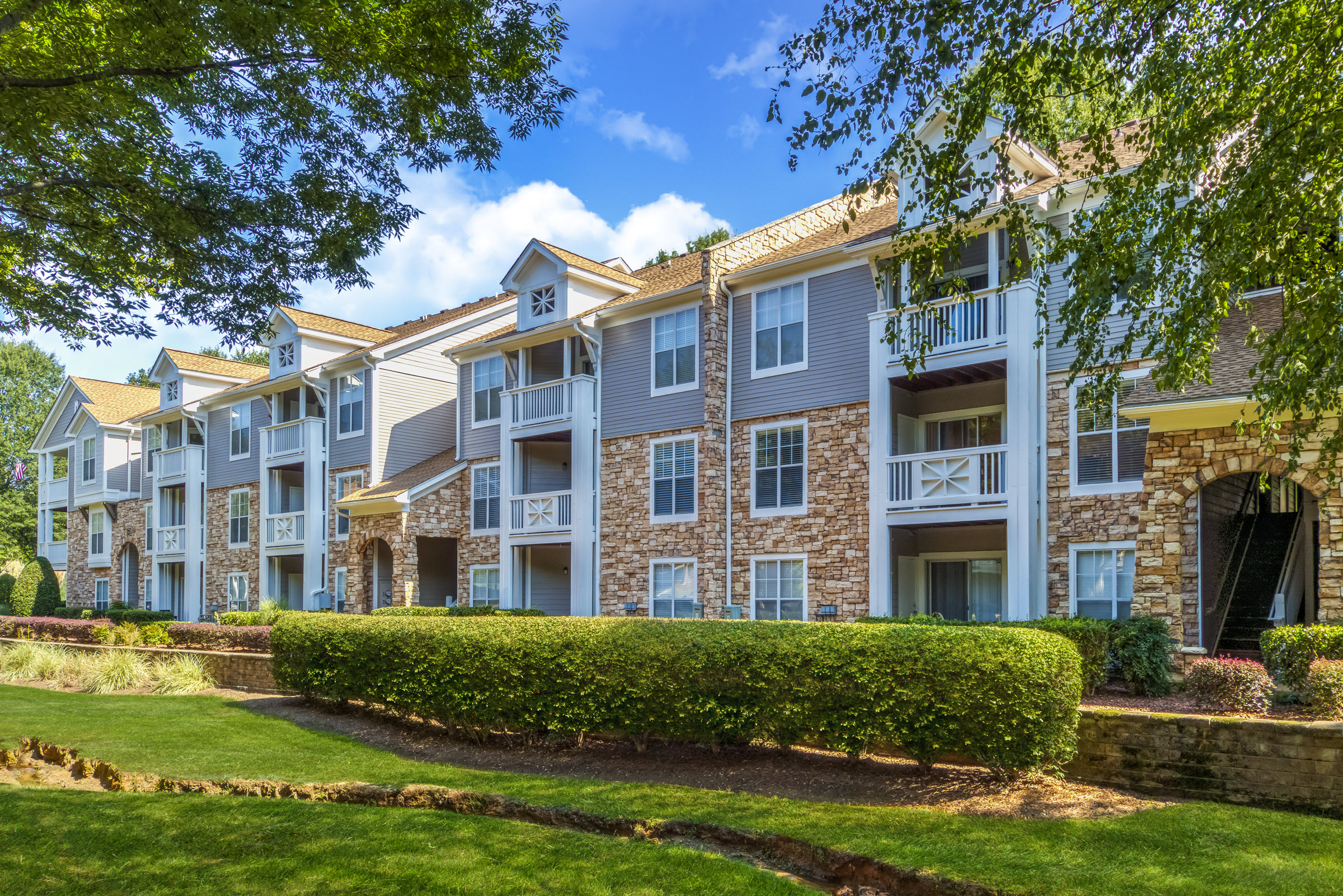 Building exterior surrounded by large trees at Camden Sedgebrook in Huntersville, NC