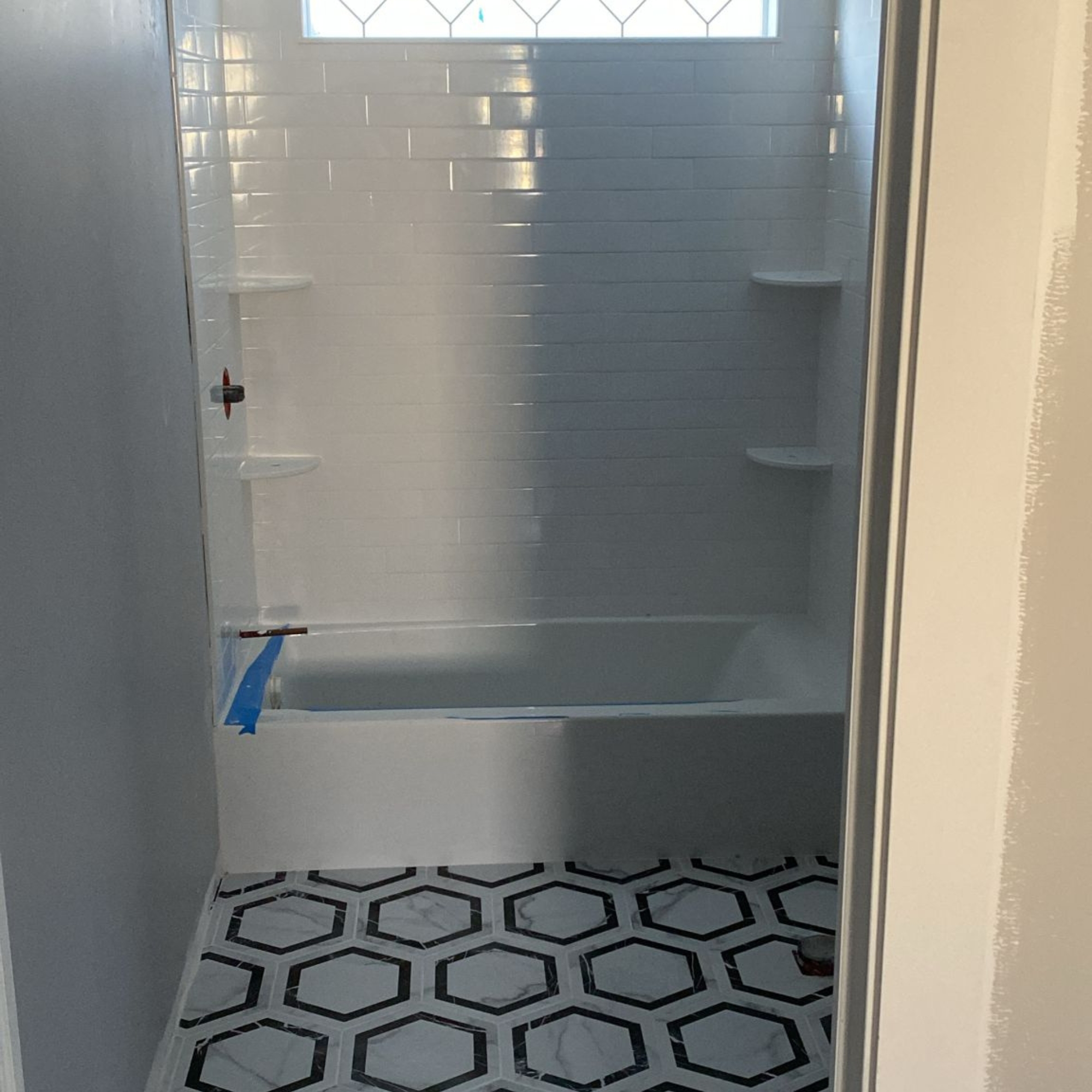 Modern walk-in shower with glass enclosure, white subway tiles, and stylish hexagonal floor tiles. A sleek and contemporary design for upgraded bathroom aesthetics.