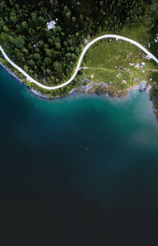 Top-down view of a forest, water, and a winding path.