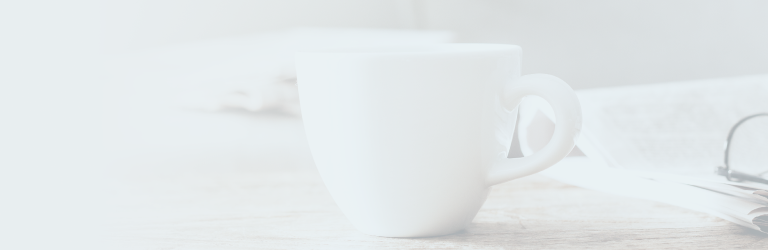 Un bureau avec un journal, une tasse et une paire de lunettes dessus.