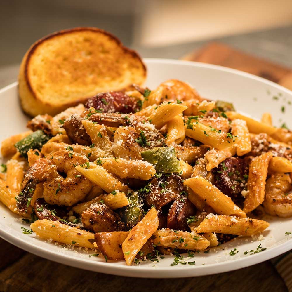 New Orleans Pasta: Shrimp, chicken, smoked sausage, peppers, onions and penne pasta in a spicy homemade Cajun alfredo sauce with garlic bread.