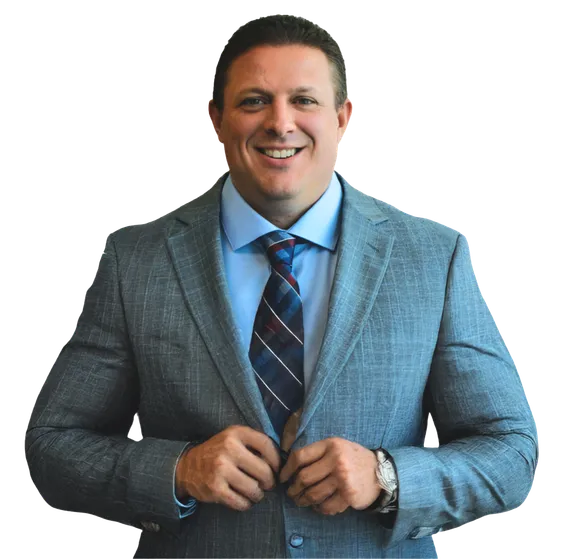 A man in a light blue suit, light blue dress shirt, and a striped tie is buttoning his jacket. He is smiling and looking directly at the camera. He is wearing a watch on his left wrist. The background is neutral and appears to be a studio or office setting.