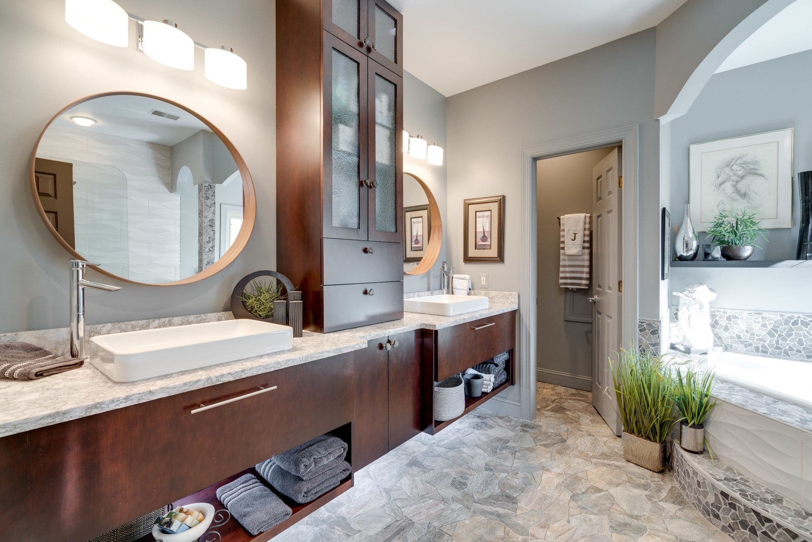 A contemporary take on the master bathroom with slab doors and warm woods.