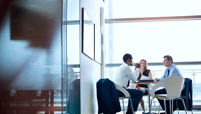 Three people sitting at an office table.