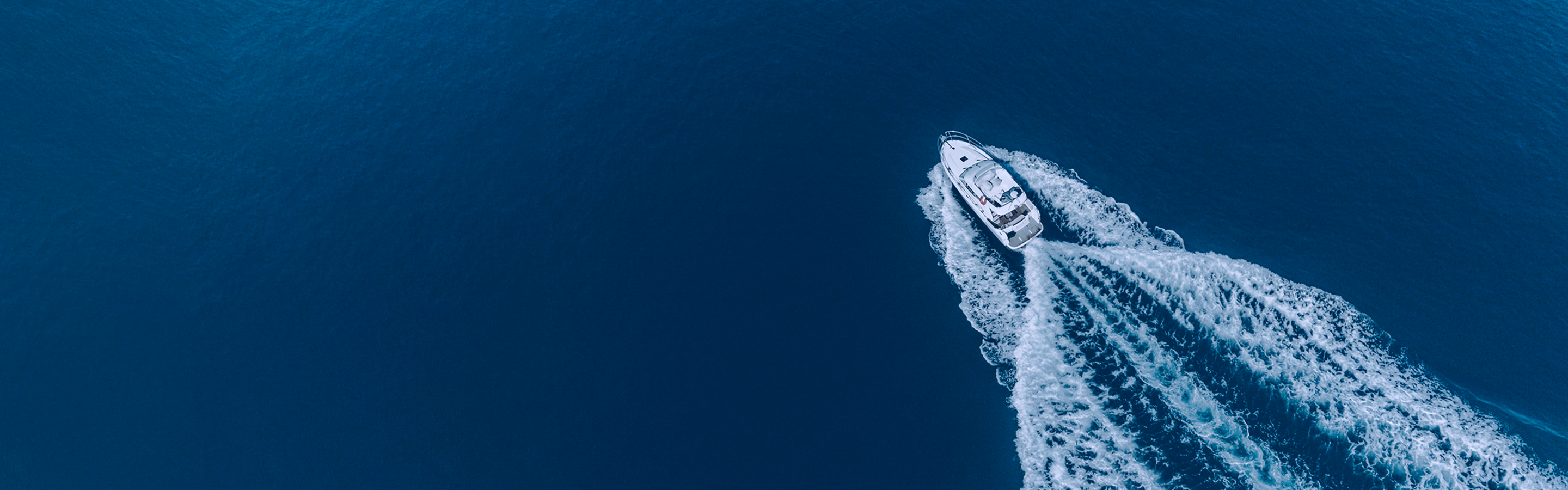Aerial view of a motorboat cutting through deep blue water.