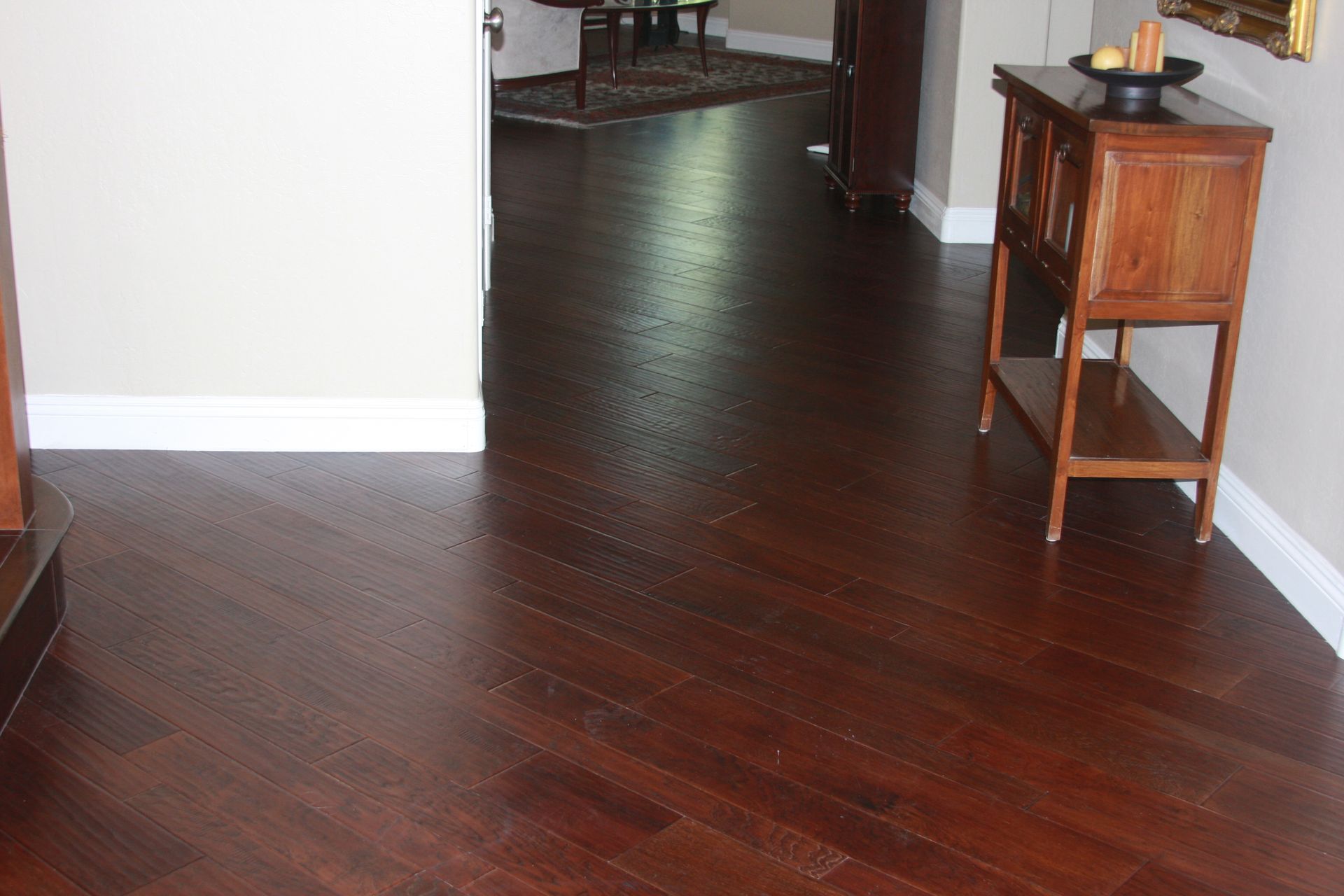 The image showcases a room with dark red hardwood flooring, laid in a diagonal pattern, leading into 