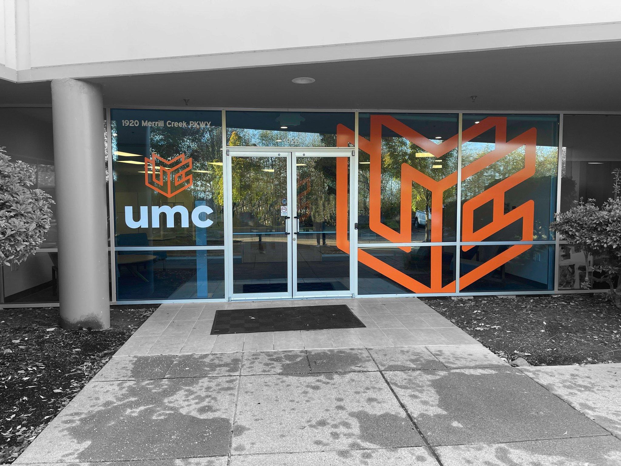 Storefront window graphics featuring UMC's logo across the entry glass, printed and installed by Ardor Printing.