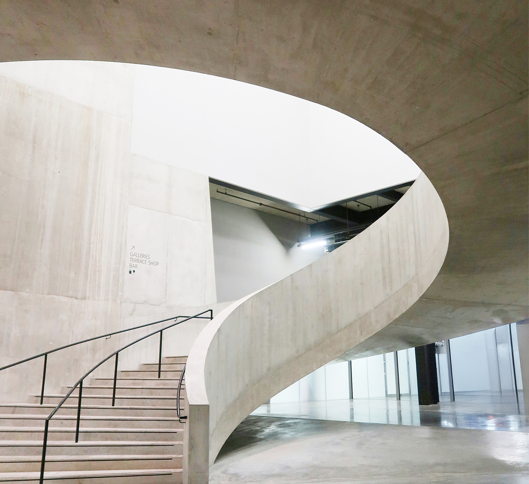 A curved, brutalist concrete staircase.