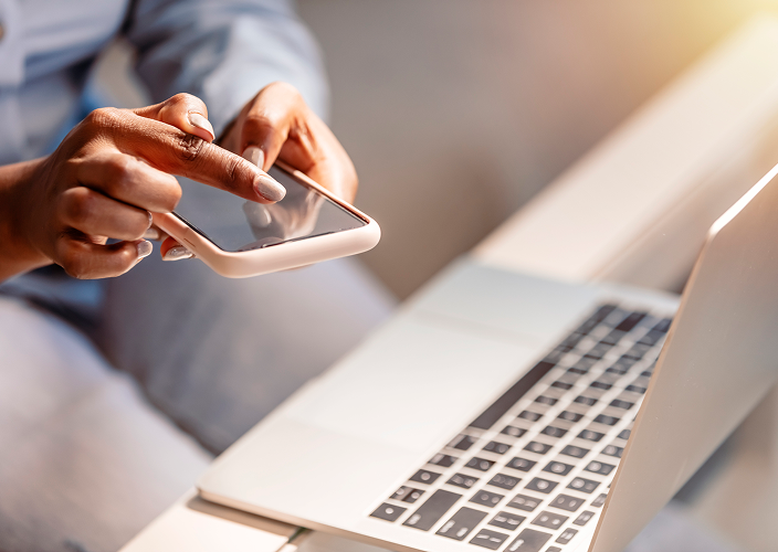Close-up of a person on their phone with their laptop in front of them.