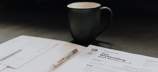 Close up of documents on a table with a coffee mug.
