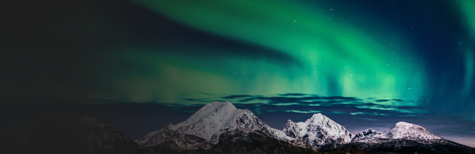The aurora borealis lighting up the sky above a snow-capped mountain range.