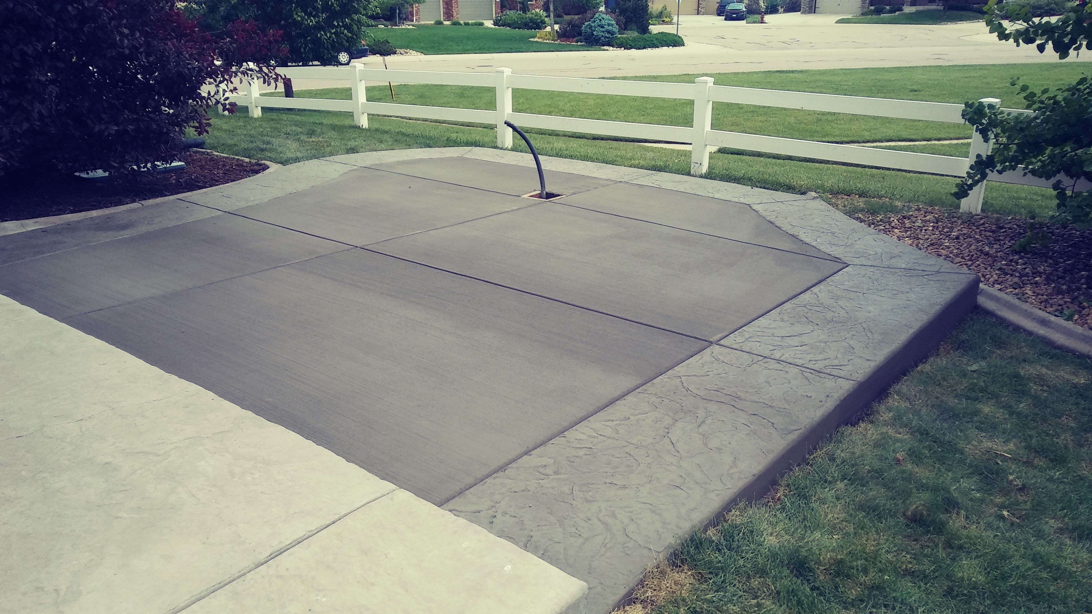 Large concrete recreational court with a smooth finished surface and decorative stamped concrete border, suitable for outdoor basketball and other activities.