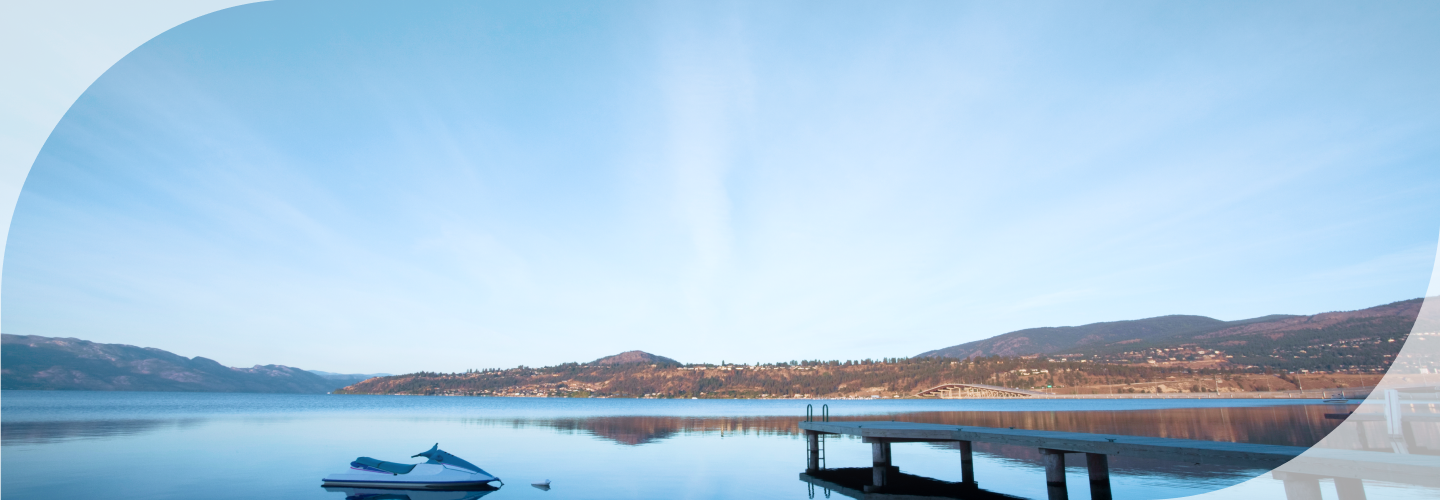 A boat floating on a lake by the dock, surrounded by rolling hills.