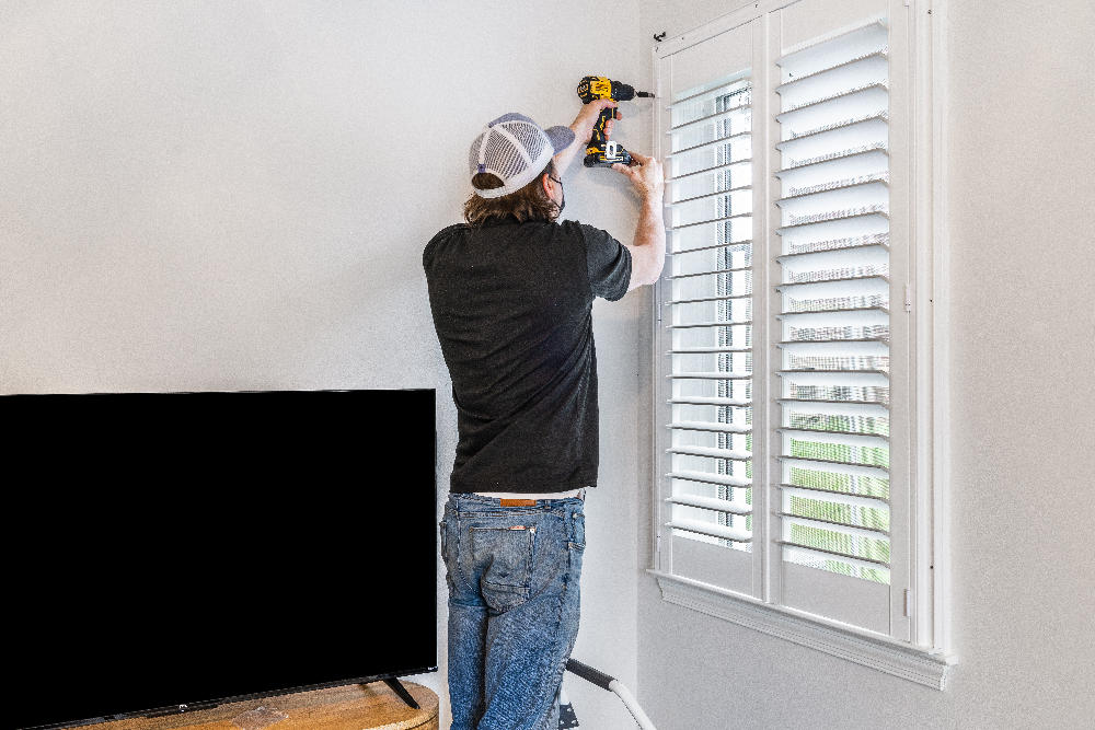 Budget Blinds of Greater Baltimore owner, Caleb, installing Norman Shutters in a Baltimore home