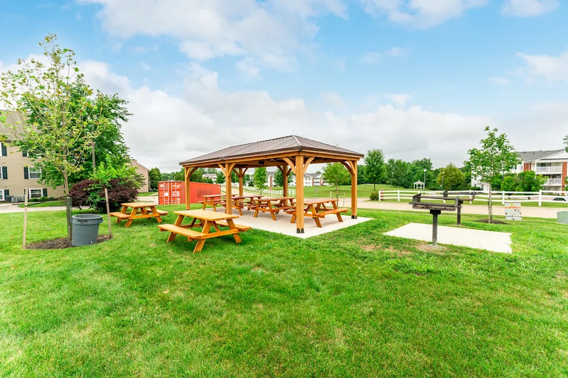 A wooden pavilion with picnic tables and grills.