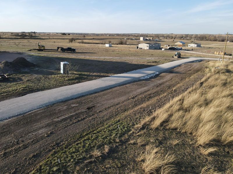 Newly constructed gravel driveway leading to rural property, highlighting excavation, grading, and driveway installation services with clean finish, proper leveling, and integration into surrounding landscape for residential access.