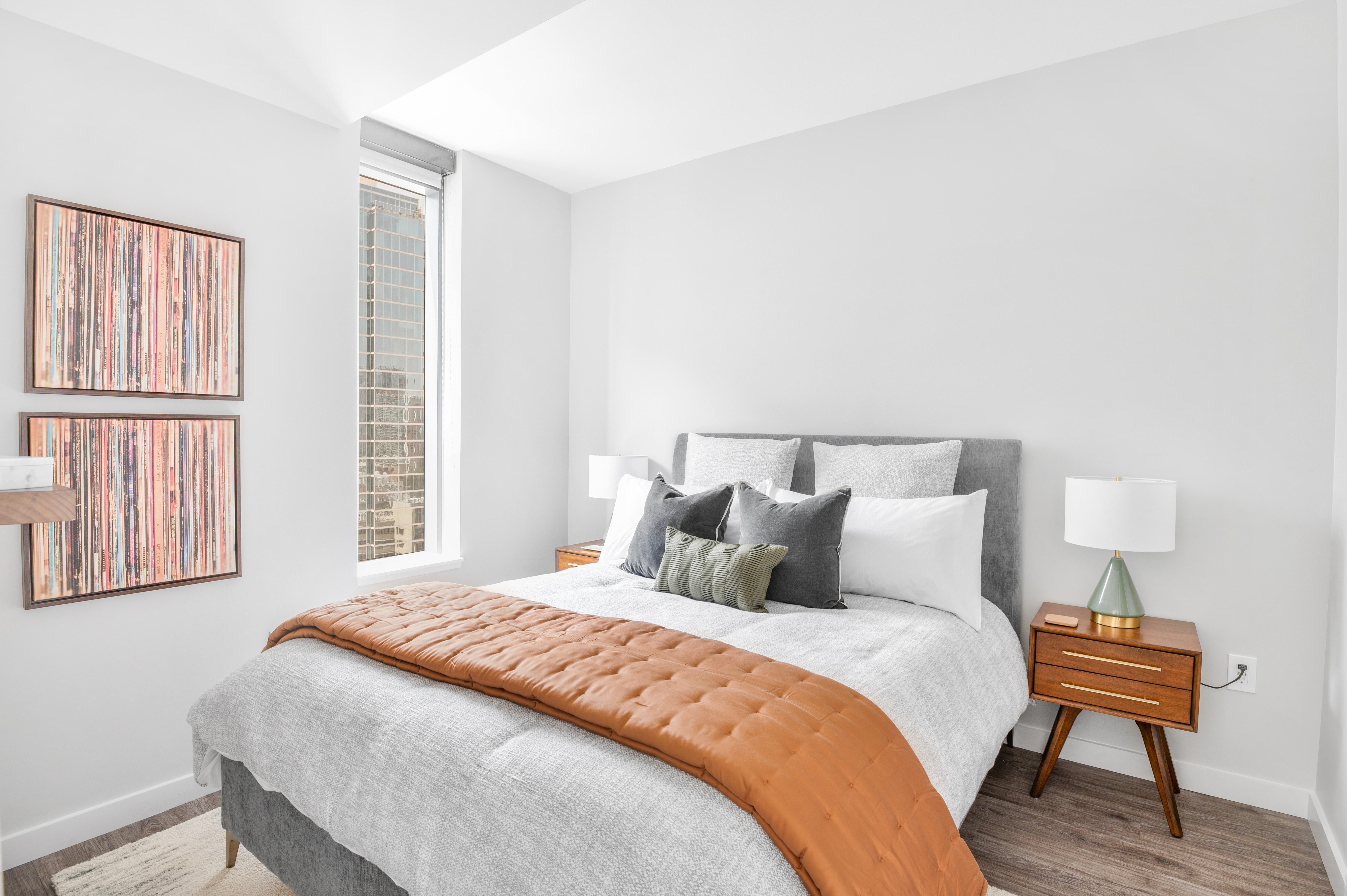 A bedroom with a bed, nightstand, and a picture on the wall. 