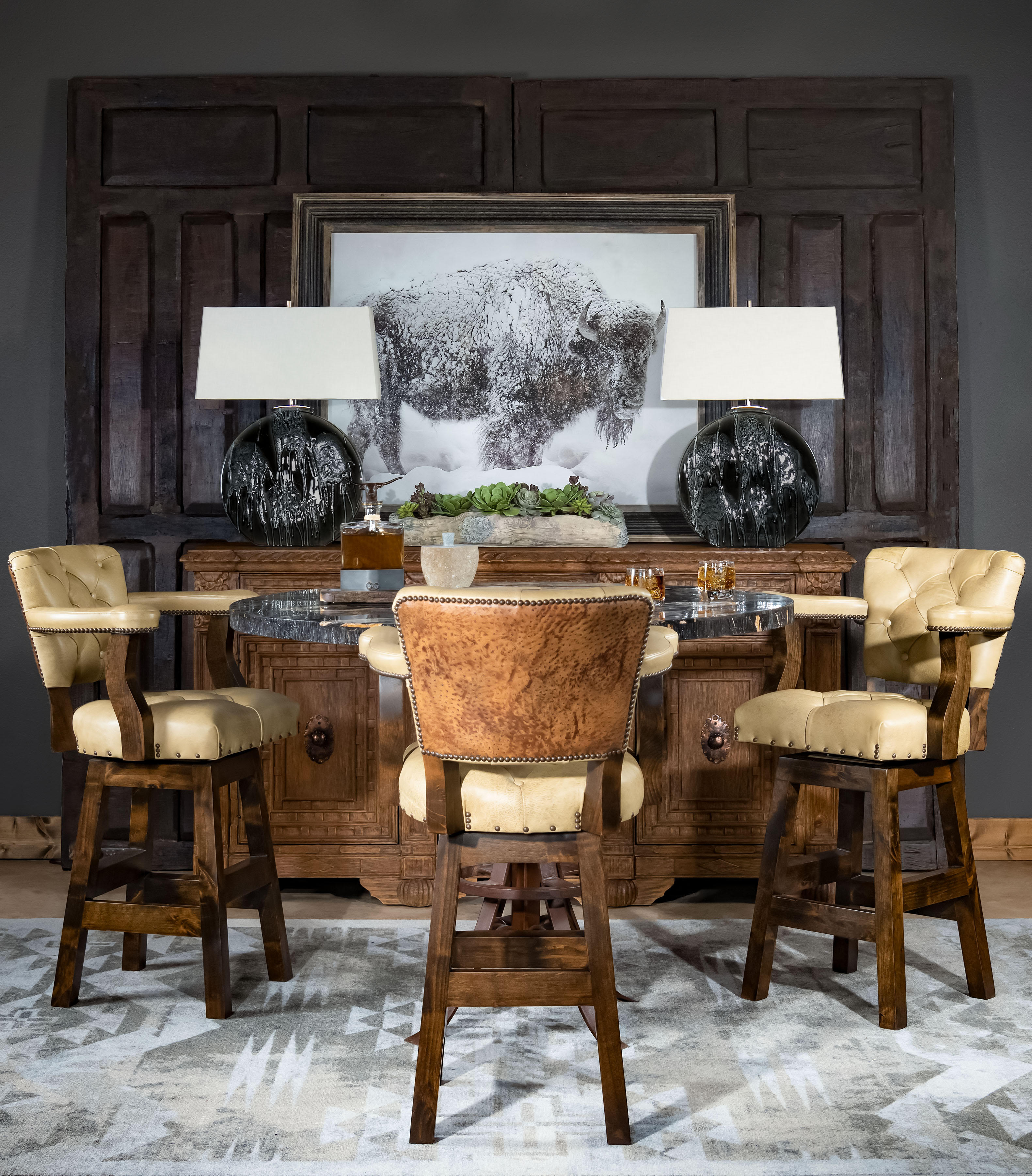 The Chisum Quill Barstool is stunning, not only for its solid hardwood framing, but particularly for its hand burnished-tufted leather with a contrasting ostrich pattern leather on the outback. Crafted to be either bar or counter height, this fine rustic barstool will make a statement in any home dining room or living area. Brass-studded accents and solid hardwood framing provide the perfect motif for this accent piece. The armrests' gentle sloping feature is a juxtaposition to the sturdily squared hard lines of the base of the barstool. All handcrafted and designed, the Chisum Quill Stool provides a uniquely authentic experience and rustic elegant charm to any space. If beauty and charm along with a stand alone character are what you seek, dive into the experience with our Chisum Quill Barstool and bring life to your home. Best as a dynamic set, these barstools are hand made classics for you. 100% American Made to the highest standards of quality and craftsmanship.