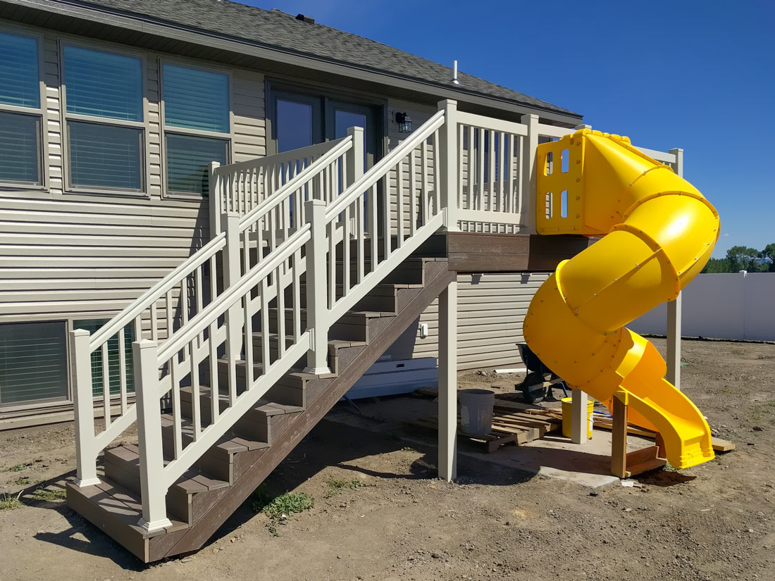 Make your backyard the ultimate family destination! This custom project by DeckPro LLC includes a durable composite deck, safe white vinyl railing, and a fun spiral slide for endless summer fun.