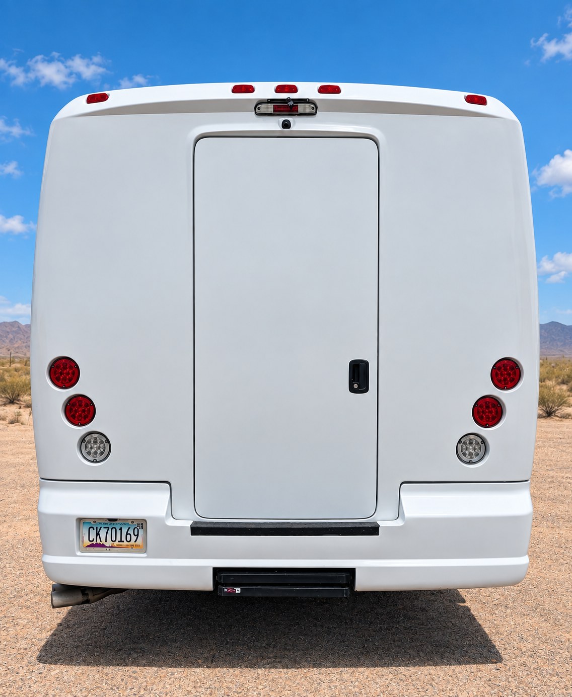 Rear view of a white passenger shuttle with double luggage doors.