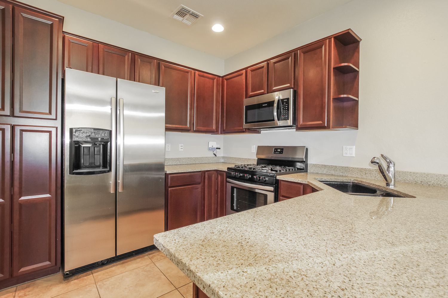 Modern kitchen with stainless steel appliances and granite countertops at Invitation Homes Phoenix.