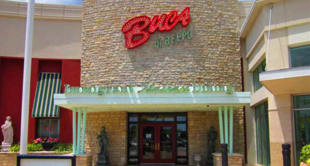 Buca di Beppo The Florida Mall exterior showing red, white brick walls, and green and white striped window accents.