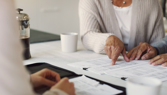 Close up of an advisor meeting with a client and reviewing documents together.