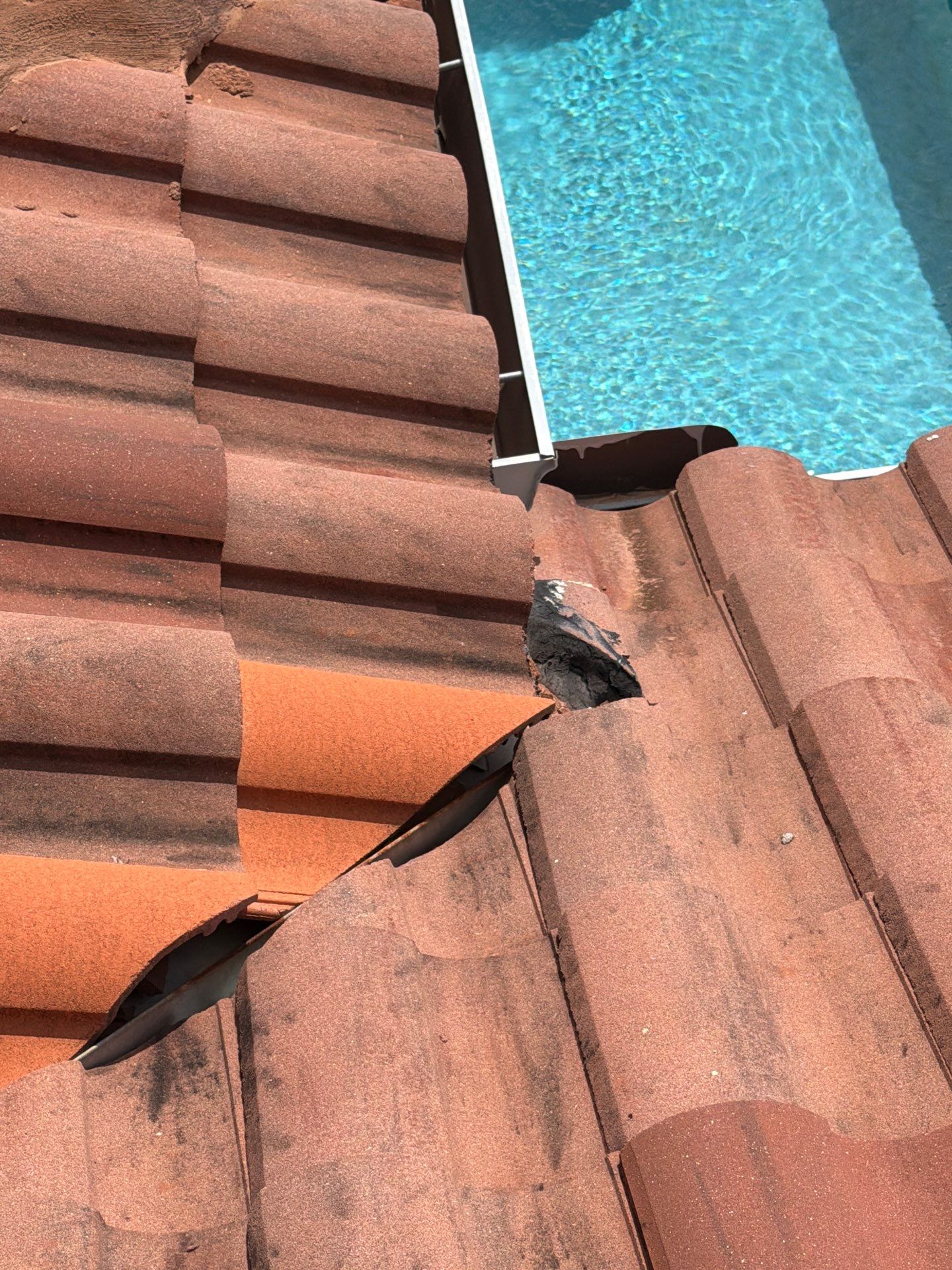 Close-up of a tile roof repair area with exposed underlayment, showing preparation work for tile rep 