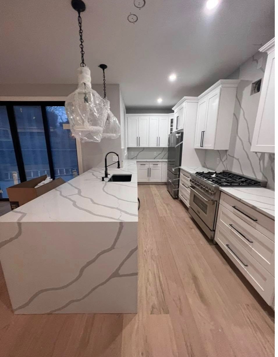 Remodelación de cocina con encimeras de cuarzo blanco con vetas grises, isla con terminación en casc 