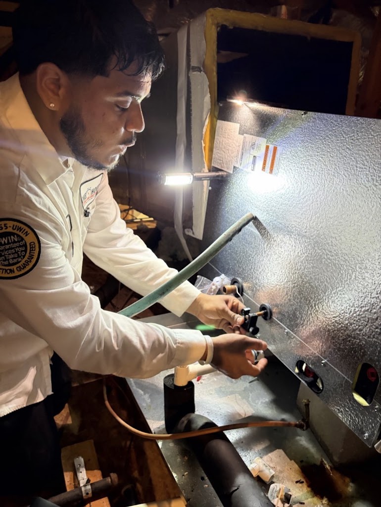 Professional and courteous One Hour Heating & Air Conditioning technician servicing an attic air han 