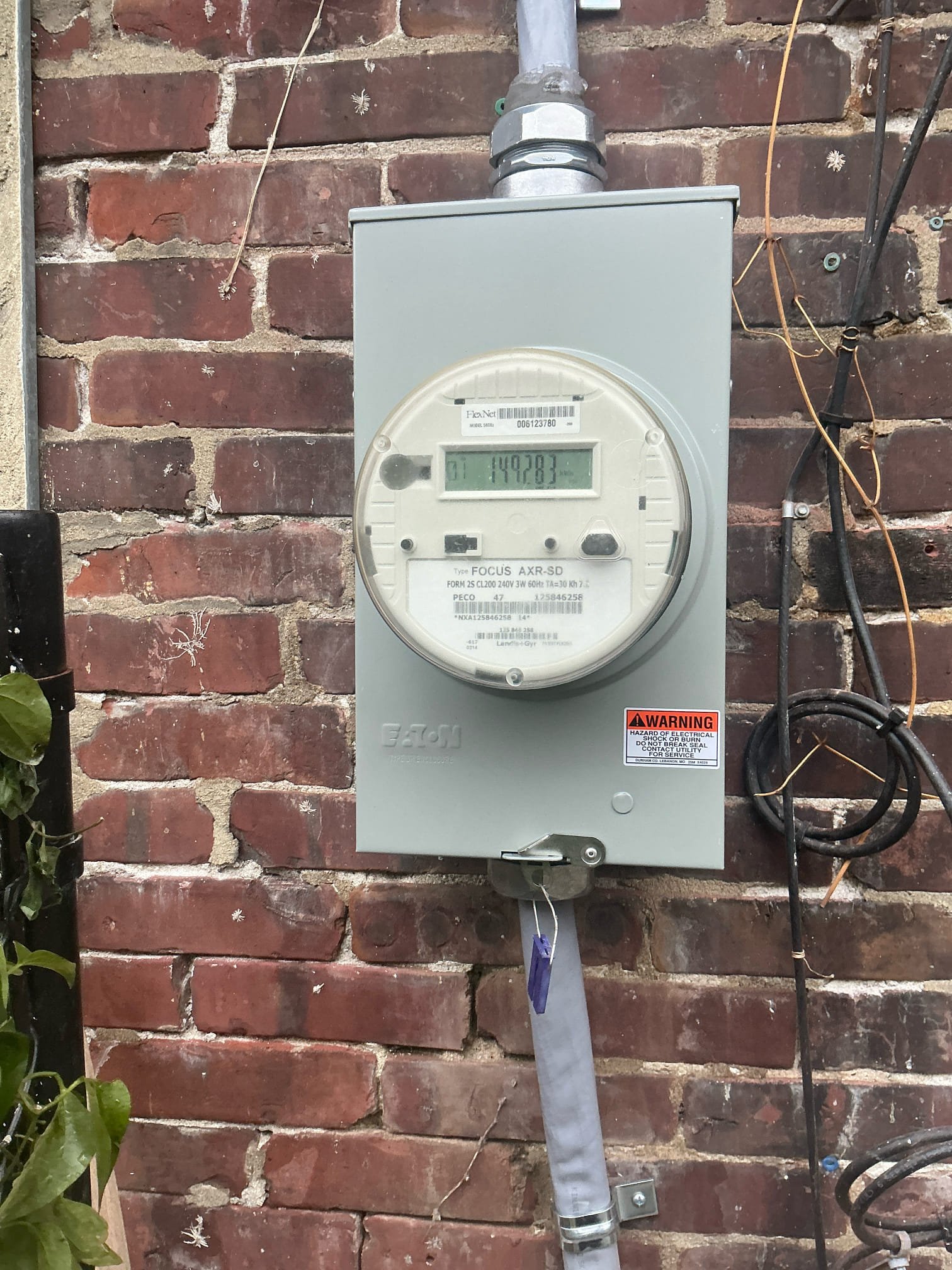 Thomas Edison Electric repaired this Eaton meter base housing a PECO Focus AXR-SD utility meter at a Philadelphia, PA rowhome. The exterior-mounted base connects the overhead service entrance to the home's electrical system.
