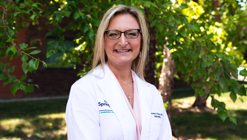 Female with short light hair wearing glasses smiling in outdoor setting