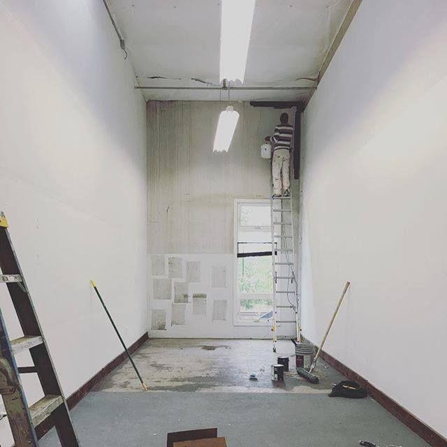 Commercial interior painting project in progress with high ceilings, wall preparation, ladders, and  