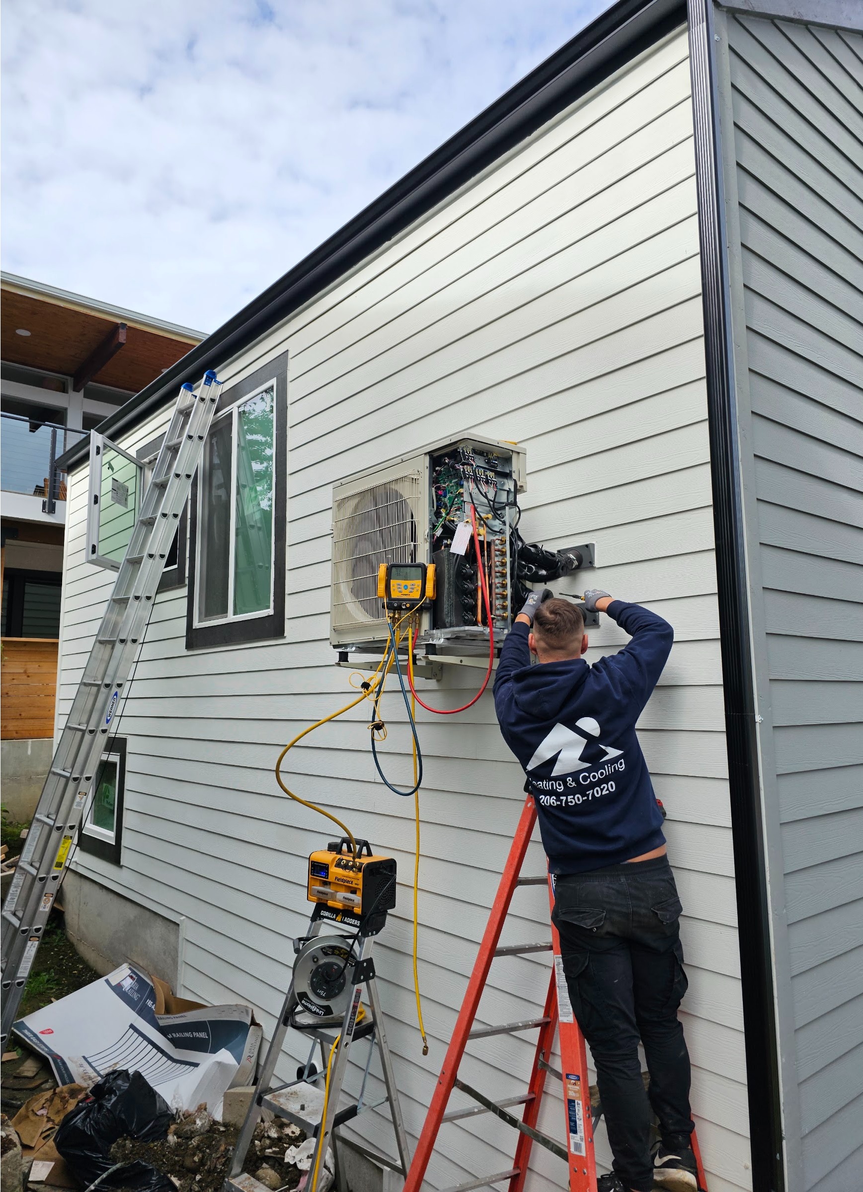 Technician on a ladder installing a ductless mini split line set on a home's exterior. Ductless mini split installation by Ready Energy Solutions.