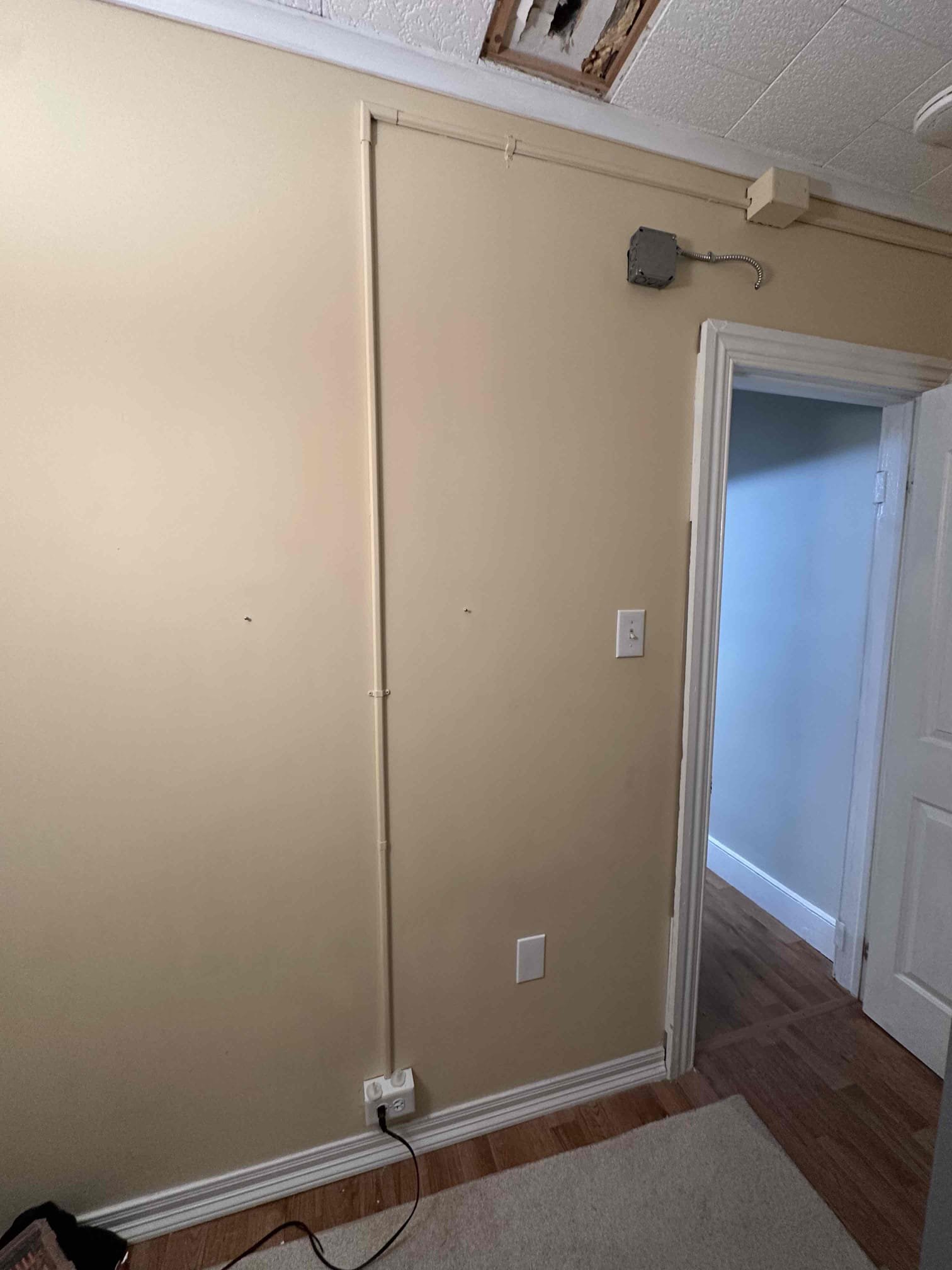 Thomas Edison Electric ran a surface-mounted Wiremold conduit channel from ceiling to baseboard in a Reading, PA home, adding a new outlet and junction box without opening up the walls. This approach is ideal for older homes where fishing wire through plaster walls is not practical.