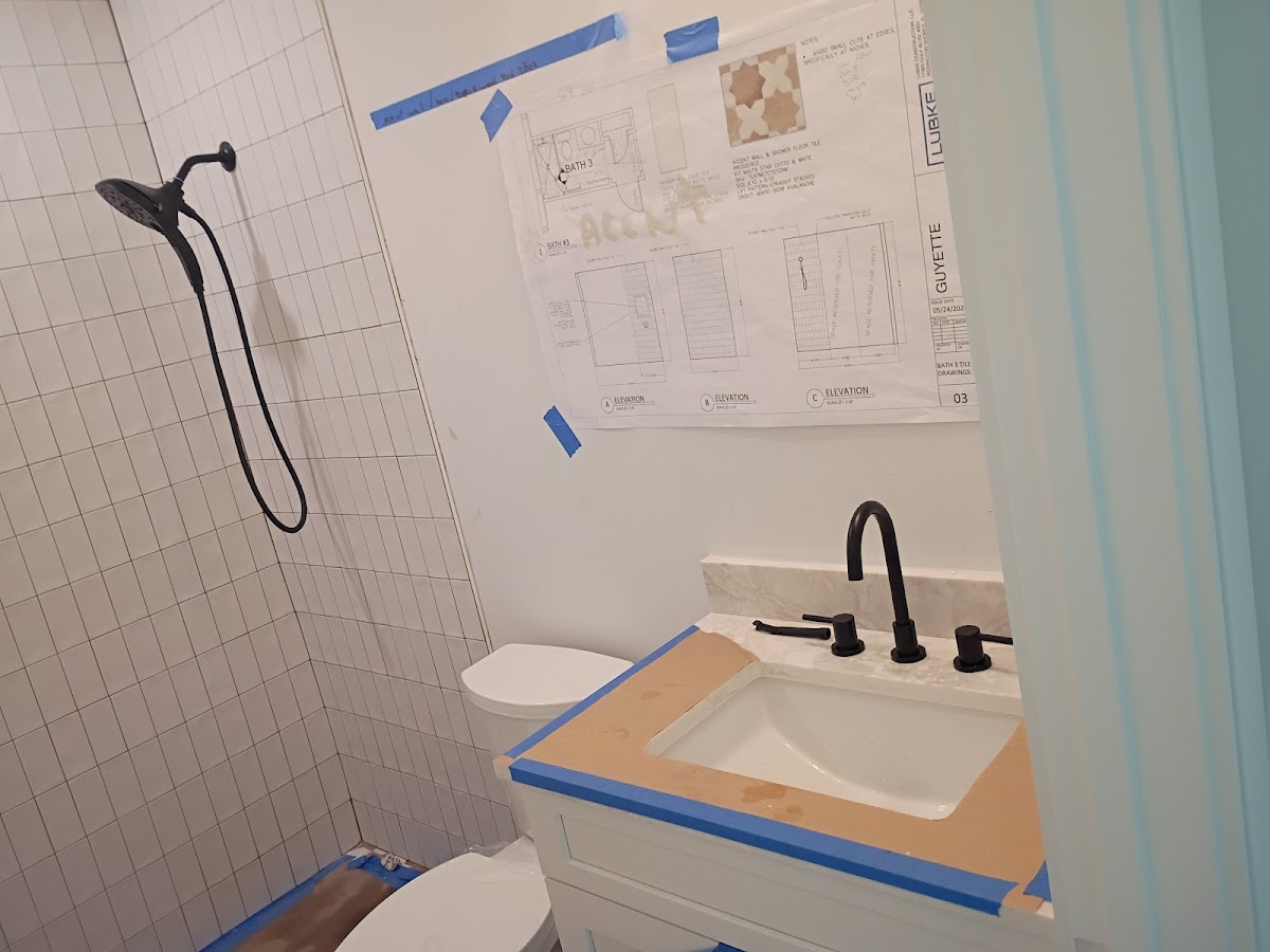 Bathroom tub and shower area prepared for plumbing or remodeling work, with protective tape and exposed wall sections during renovation.