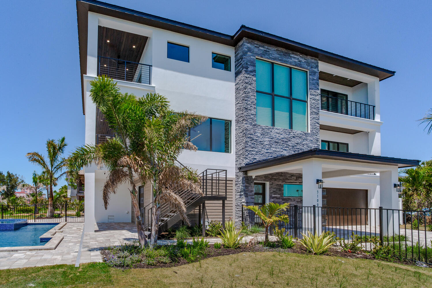 Modern coastal AVENTIS custom home exterior featuring clean architectural lines, large windows, tropical landscaping, and elevated luxury curb appeal.