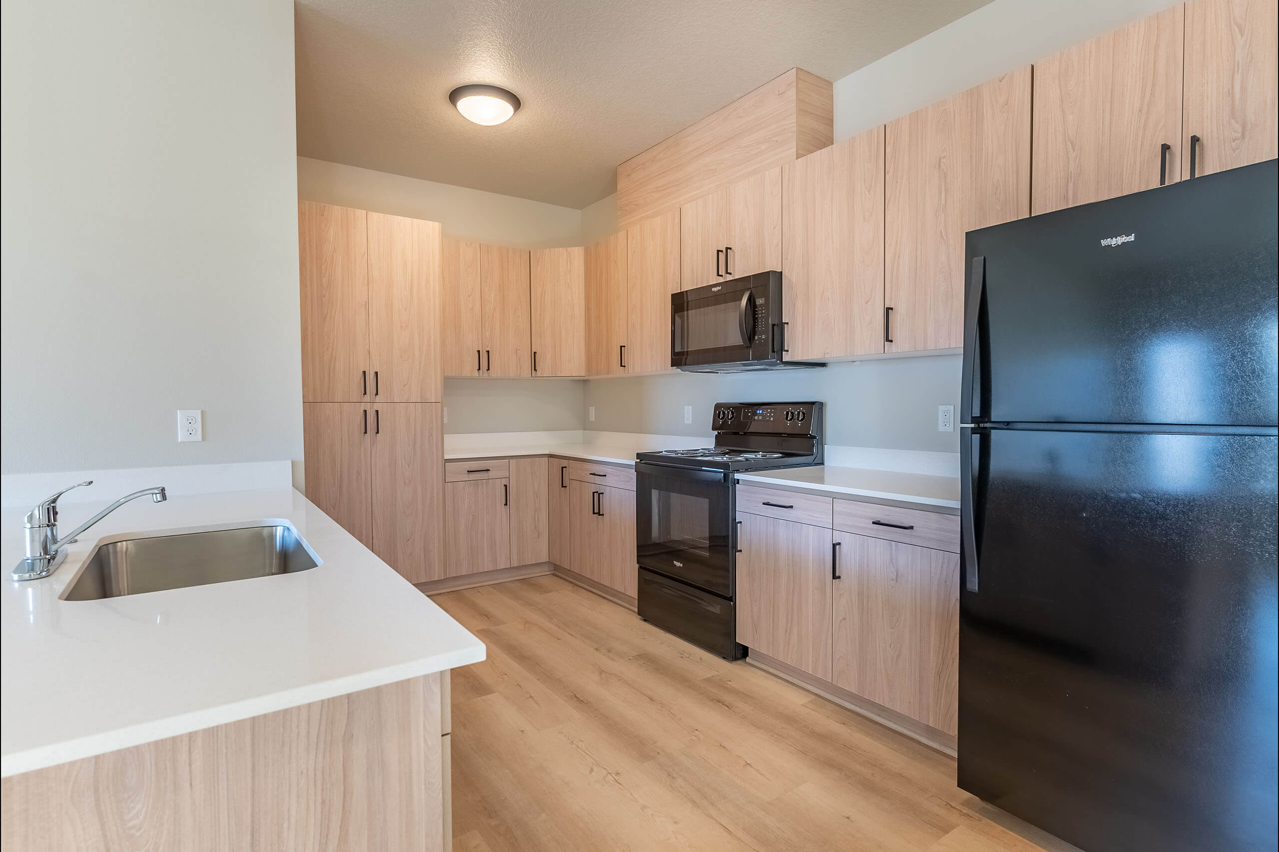 A kitchen with wooden cabinets and a black refrigerator.